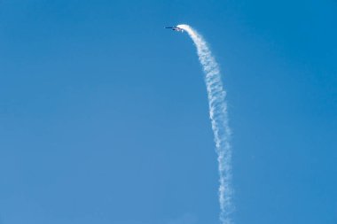 Airlie Beach, WhitSunday, Queensland, Avustralya - Nisan 2022: Eski bir Rus akrobatik uçağı gökyüzünde manevralarını gerçekleştirirken arkasında iz bırakıyor.