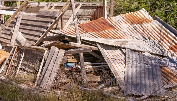 A dumped pile of old junk include sheets of rusting iron and dilapidated timber in front of an abandoned home on the gemfields Australia.