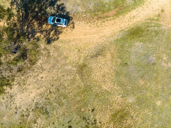 Drone return to home view overhead as it comes in to land beside a vehicle in the bush.