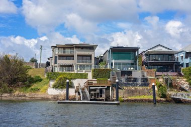 Brisbane, Queensland, Avustralya - Eylül 2022: Nehir kıyısındaki lüks evler kendi tekne iskeleleriyle. Nehir manzarası, zengin zenginler için pahalı bir yaşam tarzı..