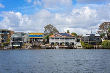 Brisbane, Queensland, Avustralya - Eylül 2022: Nehir kıyısındaki lüks evler kendi tekne iskeleleriyle. Nehir manzarası, zengin zenginler için pahalı bir yaşam tarzı..