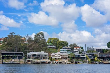 Brisbane, Queensland, Avustralya - Eylül 2022: Nehir kıyısındaki lüks evler kendi tekne iskeleleriyle. Nehir manzarası, zengin zenginler için pahalı bir yaşam tarzı..