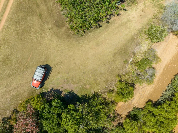 Drone returning to home with car base below on a dirt road surrounded by trees. Australia.