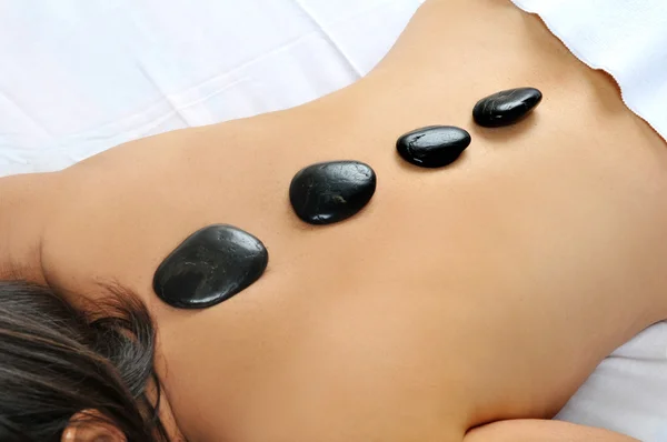 Woman laying with stones on her back Royalty Free Stock Photos