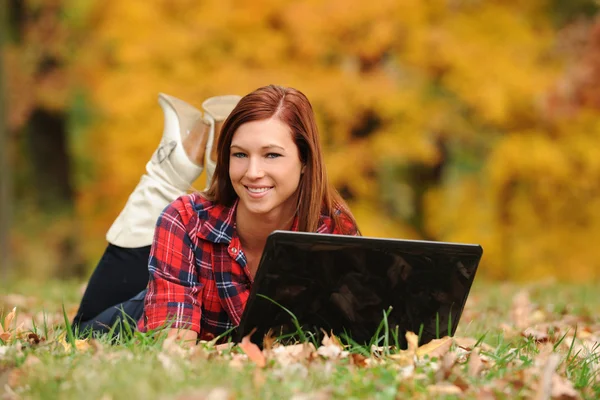 Mulher jovem que estabelece com um computador portátil — Fotografia de Stock