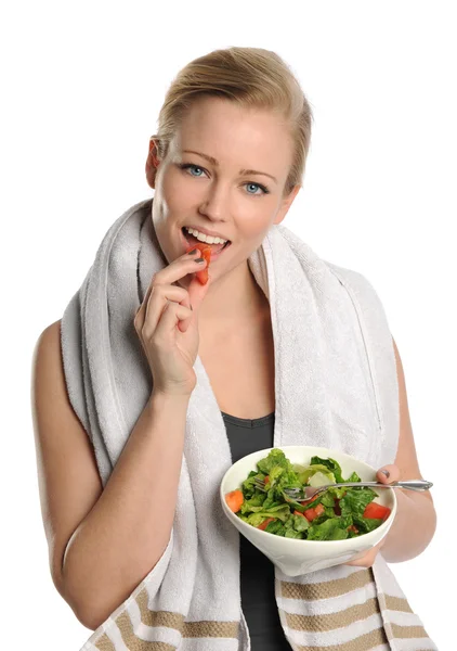 Mujer joven sosteniendo un tazón de ensalada y comiendo un pedazo de tomate — Foto de Stock
