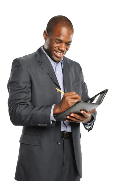 Joven sonriente hombre de negocios negro tomando notas Imagen De Stock