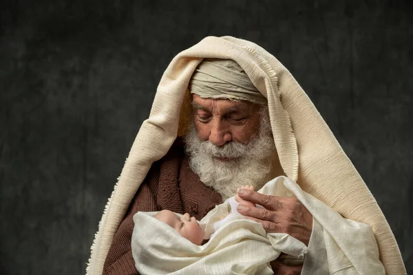 Simeon Hält Das Jesuskind Seinen Armen Vor Dunklem Hintergrund lizenzfreie Stockfotos