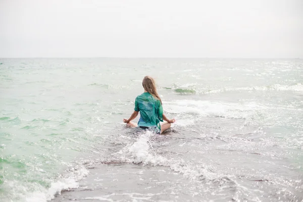 Junge Frau meditiert am Meer — Stockfoto