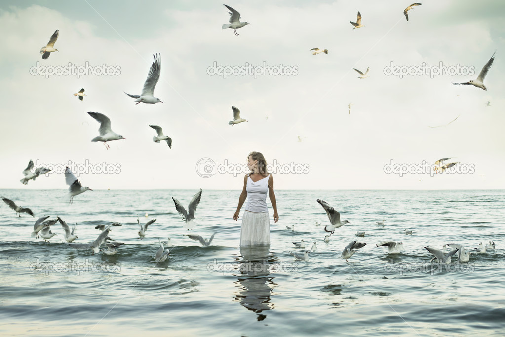 Beautiful woman and seaguls on the beach