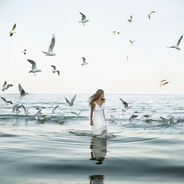 Mooie vrouw en seaguls op het strand — Stockfoto