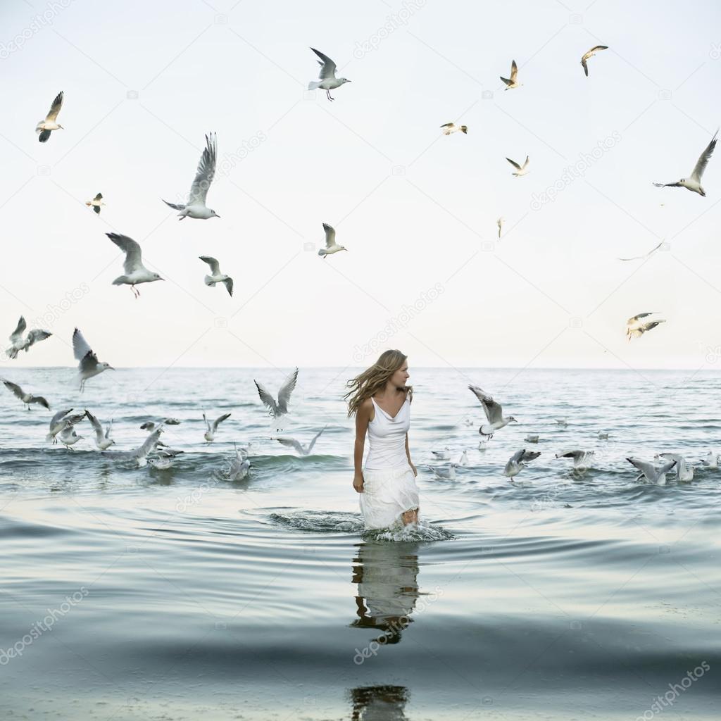 Beautiful woman and seaguls on the beach