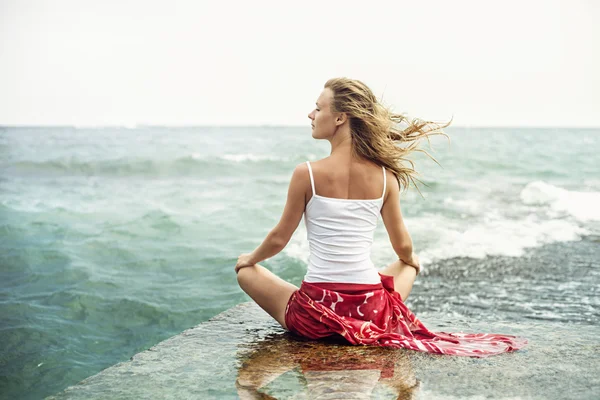 Ung kvinna meditation på stranden Stockbild