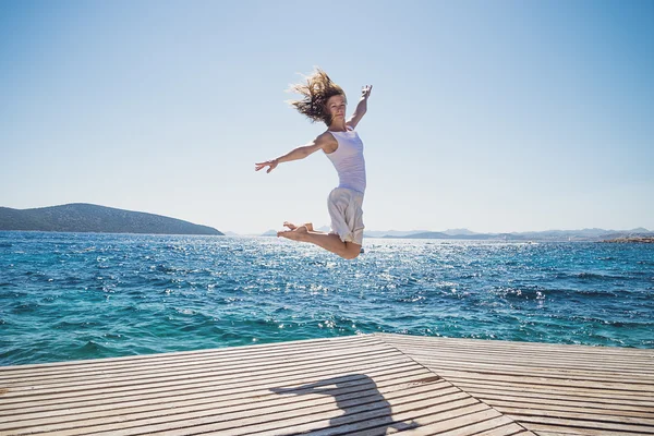 Jovem mulher pulando na praia — Fotografia de Stock