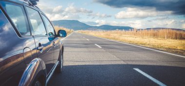 Dağ yolunda seyahat etmek için bir araba. Mavi gökyüzü