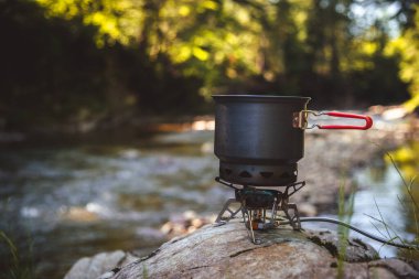 Yürüyüş sırasında kamp benzini kullanarak yemek pişirmek. Nehir. Karpatlar