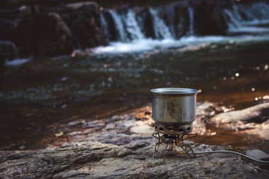 Yürüyüş sırasında kamp benzini kullanarak yemek pişirmek. Nehir. Karpatlar