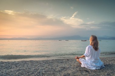 Woman meditating at the Garda Lake. Yoga practice. Sunset. Italy