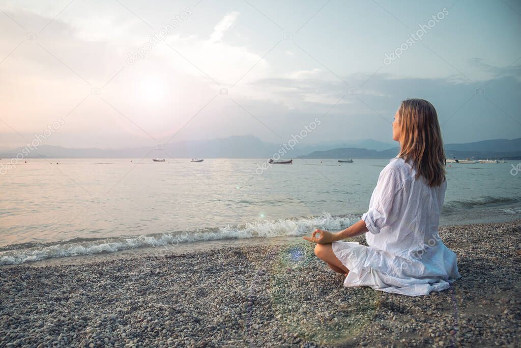 Woman meditating at the Garda Lake. Yoga practice. Sunset. Italy