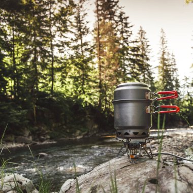 Yürüyüş sırasında kamp benzini kullanarak yemek pişirmek. Nehir. Karpatlar