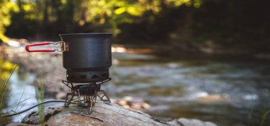 Yürüyüş sırasında kamp benzini kullanarak yemek pişirmek. Nehir. Karpatlar