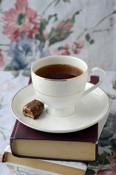 Λευκό φλιτζάνι τσάι με γλυκά σε μια στοίβα από βιβλία — Φωτογραφία Αρχείου