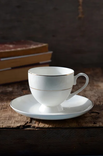 Copa blanca sobre una mesa de madera con libros — Foto de Stock