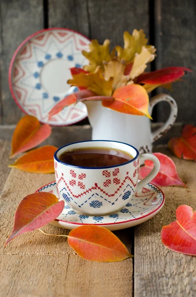 Een kopje thee op de tabel met herfst bladeren — Stockfoto