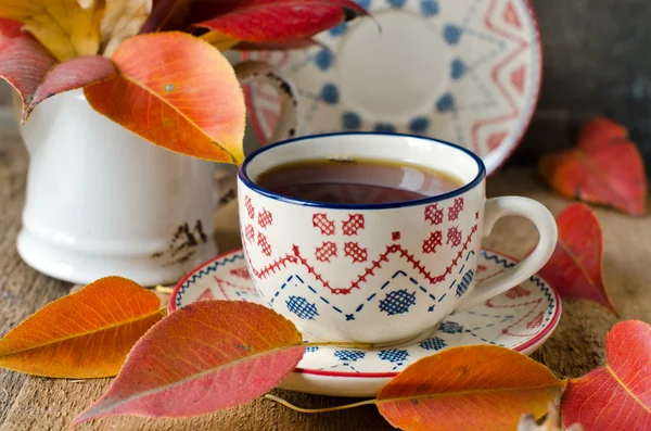 Чашка чая на столе с осенними листьями — стоковое фото