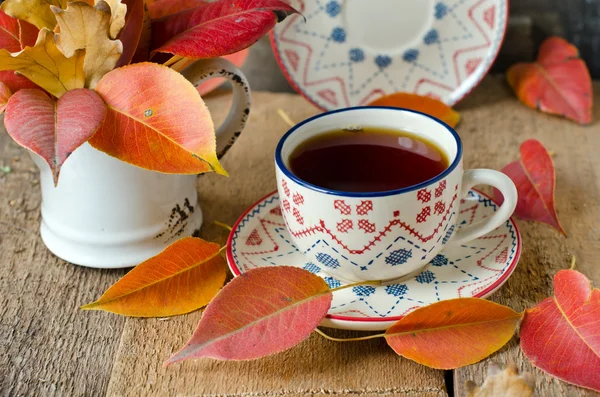 Eine Tasse Tee auf dem Tisch mit Herbstblättern — Stockfoto
