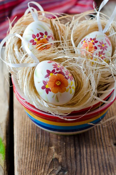 Painted Easter eggs in a bowl on a wooden table — Stock Photo, Image