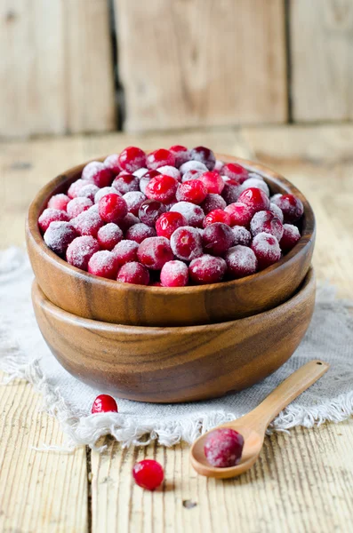 Cranberries in a wooden bowl on a wooden table — Stock Photo, Image