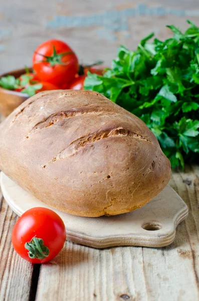 Homemade bread on wooden table with fresh vegetables — Stock Photo, Image