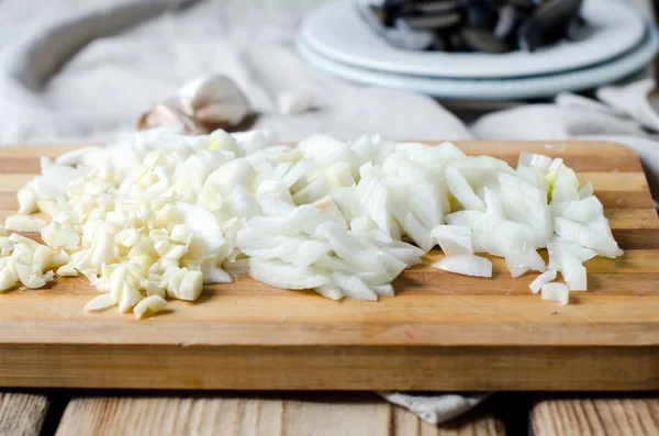 Chopped onion and garlic on a cutting board — Stock Photo, Image