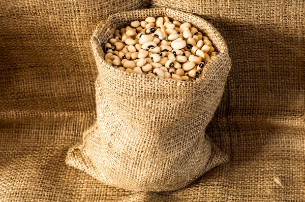 Black eyed peas in jute bag on jute background — Stock Photo, Image