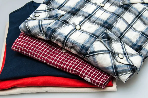 Pilha de camisas e camisetas em cores diferentes isoladas em branco — Fotografia de Stock