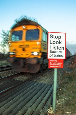 Beware of trains concept image with moving train in background clipart