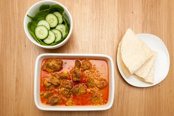 Cordeiro de caril indiano rogan josh em um prato branco, com pão naan . — Fotografia de Stock