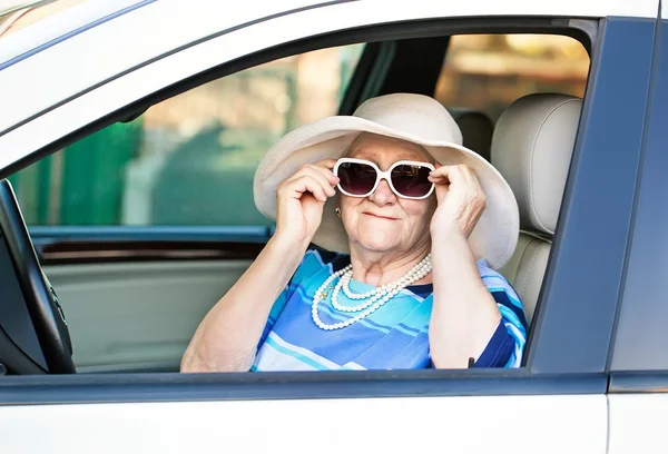 Vecchia donna con gli occhiali da sole seduta in macchina — Foto Stock