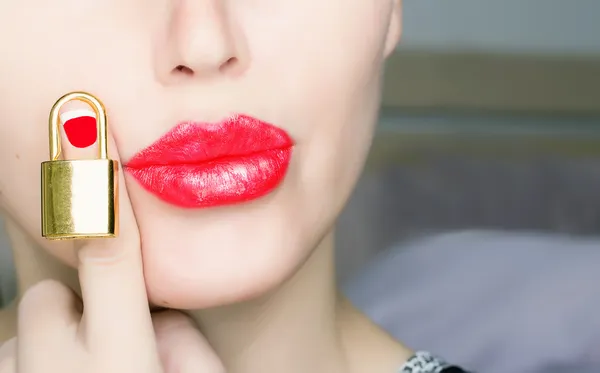 Kvinna med röda läppar hålla guld lås — Stockfoto