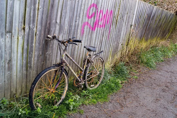 An abandoned bike left on a foot path upright and getting dirty every day.