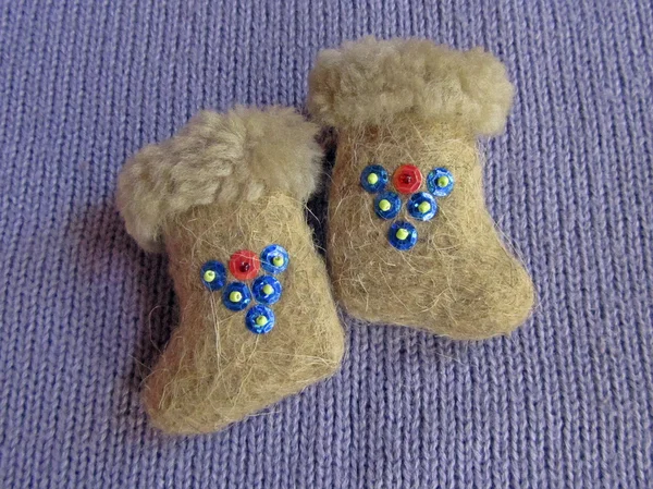Small felt boots with sequins on violet sweater closeup