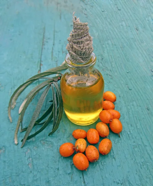 Sea ​​buckthorn oil in jar on blue wooden background, close- — Stock Photo, Image