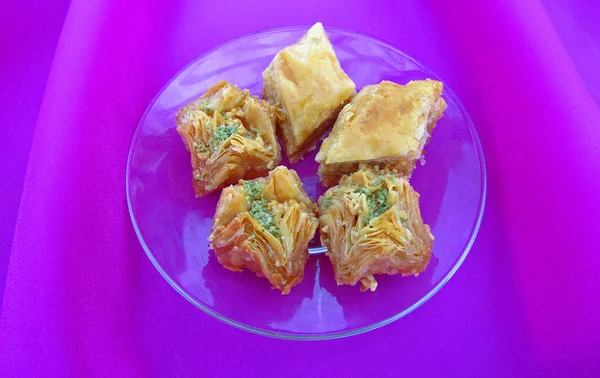 Sweet baklava on saucer on pink tablecloth, close-up — Stock Photo, Image