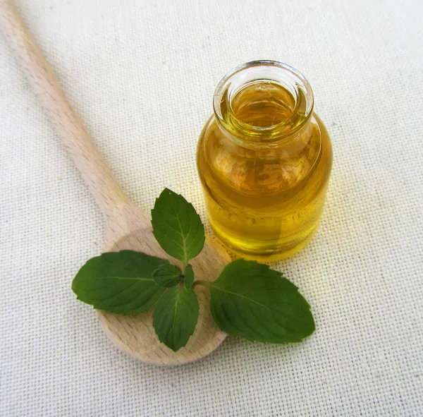 Bottiglia di olio di menta piperita con cucchiaio di legno, primo piano — Foto Stock