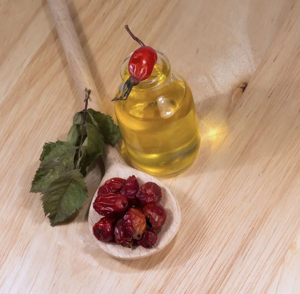 Botella con aceite y bayas secas de rosa mosqueta, primer plano — Foto de Stock