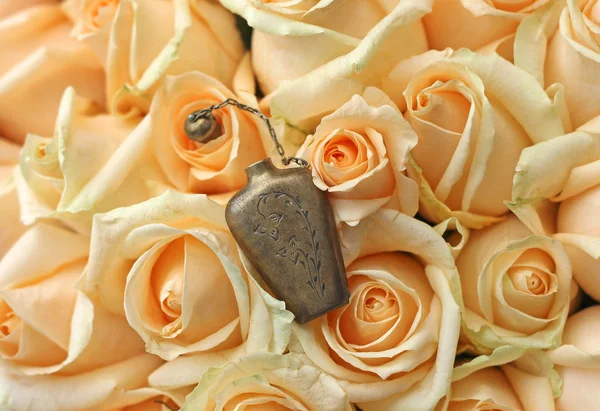 Metal perfume bottle on beautiful roses background — Stock Photo, Image