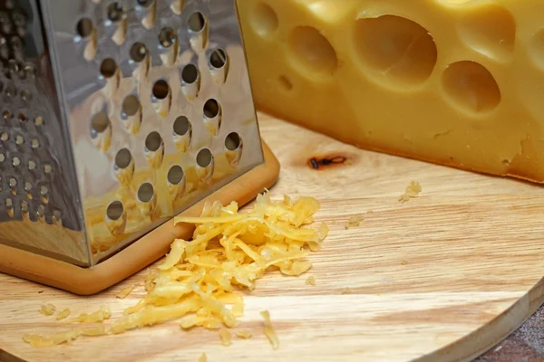 Cheese grater on wooden background, close-up