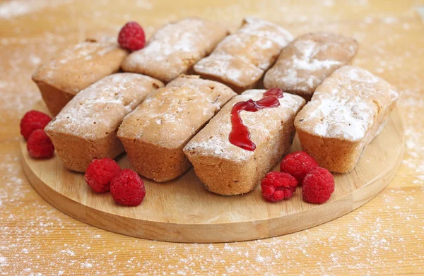 Deliciosos bolos com framboesas em fundo de madeira, close-up — Fotografia de Stock