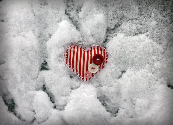 Coração listrado vermelho no fundo da neve, close-up — Fotografia de Stock